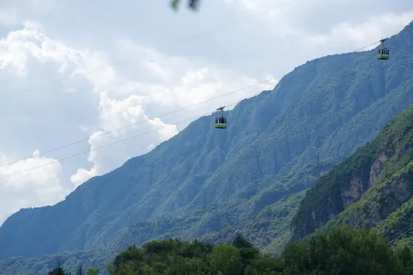 Teleférico a subir uma encosta verde