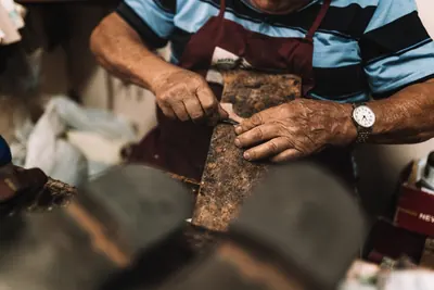 Mãos a cortar pele numa oficina de calçado